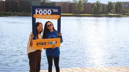 Three female students talking and laughing while walking down campus sidewalk