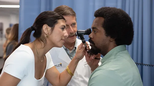 Professor looks on as physician assistant student examines the eye of another student